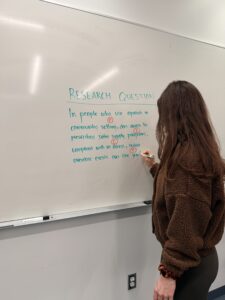 Student refining a research question on a whiteboard